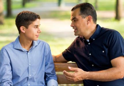 Father and son talking on park bench